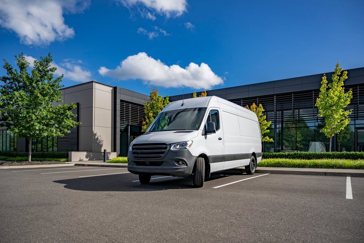 Industrial local carrier compact white maneuverable and economical cargo mini van making timely delivery to customer work place standing on the industrial parking lot for unload the goods